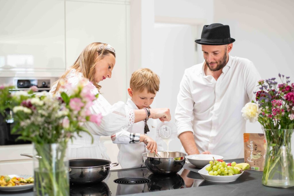 Eine Familie kocht gemeinsam in der Küche. Ein inspirierender Moment für Kochanfänger, um mit Gewürztipps und Tricks den Einstieg in die Küche zu finden.